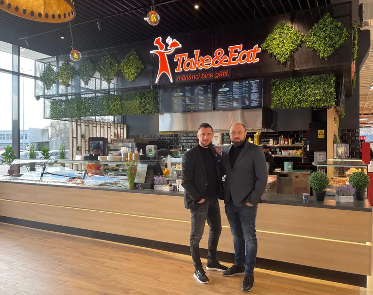Fondatorii Take&Eat, Bogdan Ichim și Daniel Crenganiș, în fața unui restaurant